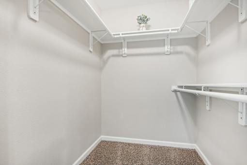 a spacious walk in closet in a home with white walls and a roll in shower at The Glen at Highpoint, Dallas, 75243