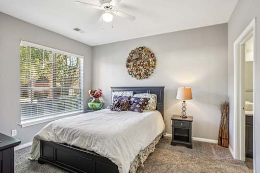 A bedroom with a bed, nightstand, and window. at Bridford Lake Apartments, Greensboro, 27407