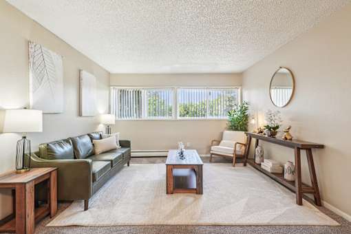 A living room with a green couch, a coffee table, and a mirror on the wall.