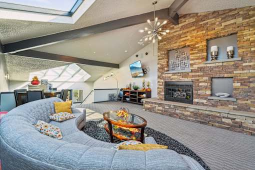 A living room with a grey couch and a stone fireplace at Union Heights Apartments, Colorado Springs, Colorado