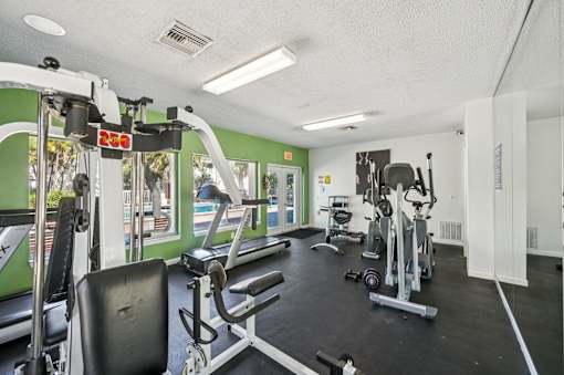 A gym with a treadmill, weights, and exercise equipment. at Sarasota South Apartments, Bradenton