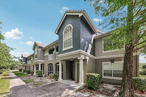 A house with a grey front and a tree in front at The Parkway at Hunters Creek, Orlando, 32837