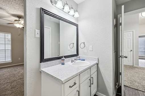 A bathroom with a sink, mirror, and a ceiling fan.