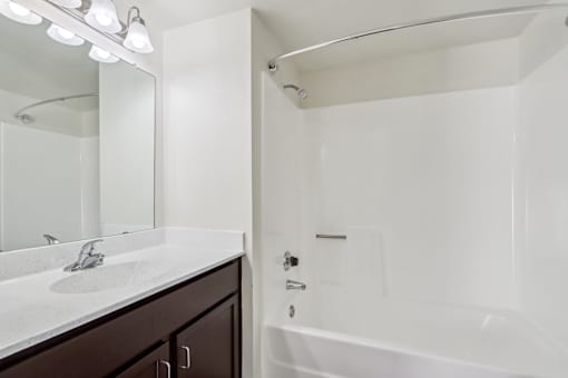 A white bathroom with a sink, mirror, and bathtub at Del Coronado Apartment, Mesa, AZ, 85202