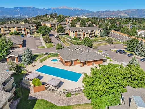 A large apartment complex with a swimming pool and a view of mountains in the background.