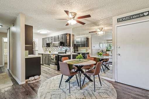A kitchen with a dining table and chairs in the middle of the room.