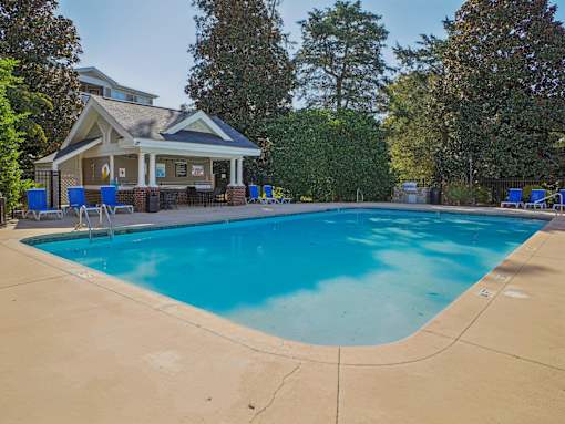 A large swimming pool in front of a house with a covered patio. at Cedar Springs Apartments, Raleigh