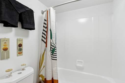 A white bathroom with a toilet, a shower curtain, and a towel rack. at Millennium at Creve Coeur, Missouri, 63141