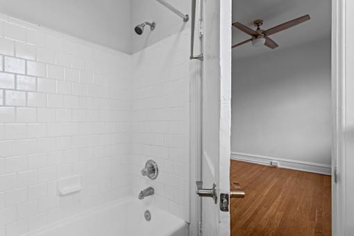 A white tiled bathroom with a wooden floor and a ceiling fan.at The Collection of Historic Richmond, Richmond