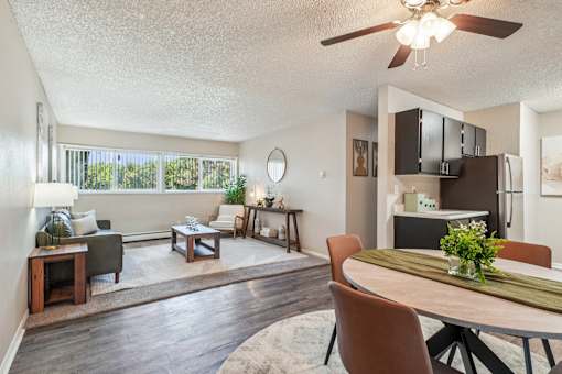 A well-lit, spacious living room with a dining area and a kitchenette.