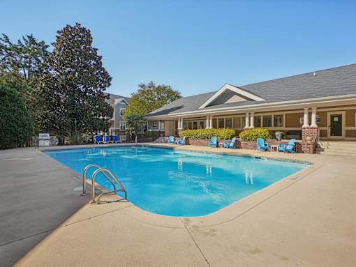A swimming pool with a diving board and lounge chairs. at Cedar Springs Apartments, Raleigh, North Carolina