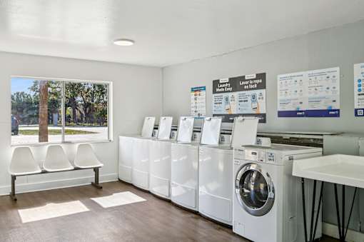 A laundromat with rows of washing machines and a bench. at Sarasota South Apartments, Bradenton