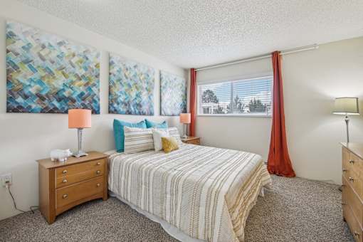 A bedroom with a bed, nightstand, and two wall art pieces at Spyglass Creek, Denver, 80224