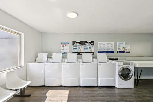 A row of white washing machines are lined up in a room. at Sarasota South Apartments, Florida