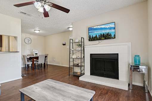 A living room with a fireplace and a television mounted above it.