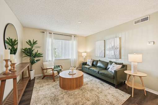 A living room with a green couch, a wooden coffee table, and a large mirror on the wall. at Sarasota South Apartments, Bradenton, FL, 34207