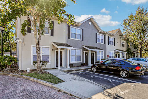 Exterior of two story townhomes with parking spaces at The Arbor Walk Apartments, Florida, 33617