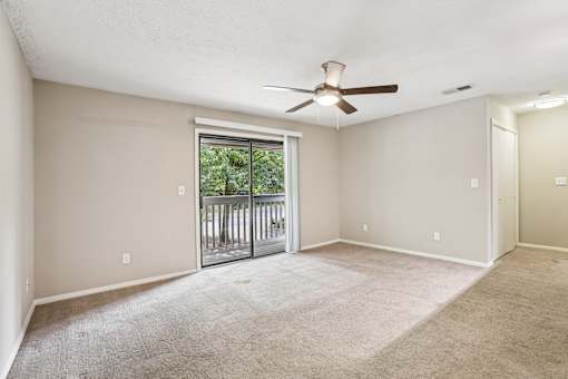 A room with a ceiling fan and sliding glass doors leading to a balcony. at Canopy Glen, Norcross, GA, 30093
