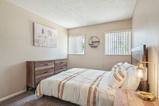 A bedroom with a bed, nightstand, and a painting on the wall.