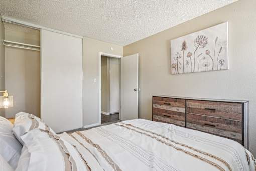 A bedroom with a bed, dresser, and a painting on the wall.