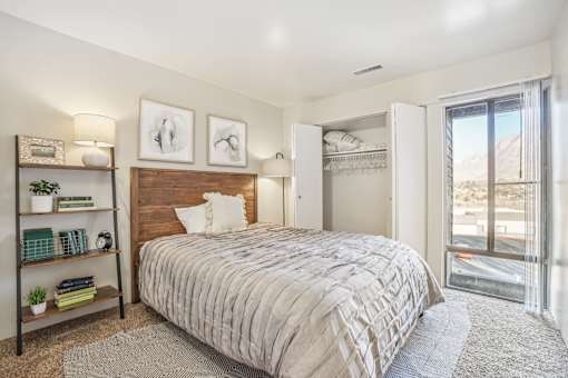 A bedroom with a large bed, a wooden headboard, and a window with a view of the mountains. at Cliffs at Canyon Ridge, Utah, 84401
