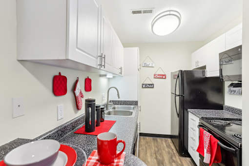 A kitchen with black appliances and red accents. at Millennium at Creve Coeur, Creve Coeur, 63141