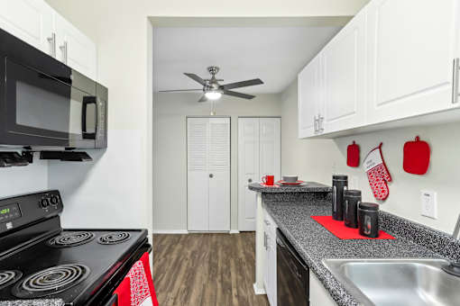 A kitchen with a black stove top oven and a black microwave above it. at Millennium at Creve Coeur, Creve Coeur, 63141