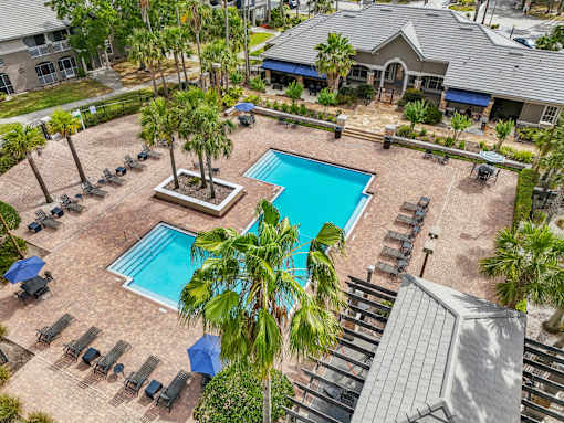 A pool surrounded by palm trees and lounge chairs at The Parkway at Hunters Creek, Orlando, 32837