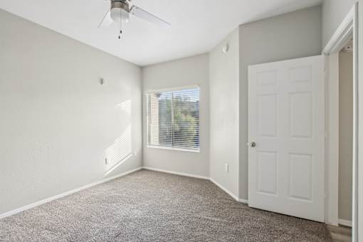 A room with a ceiling fan and a door. at Sweetwater At Metro North Apartments, Arizona 85029
