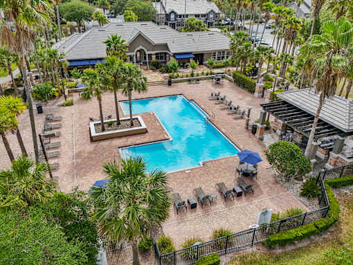 A pool surrounded by palm trees and lounge chairs at The Parkway at Hunters Creek, Orlando, 32837