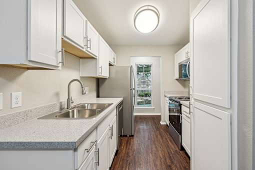 A kitchen with white cabinets and a wooden floor.
