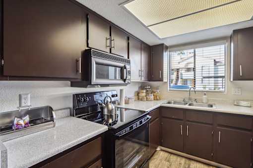A kitchen with brown cabinets and a black stove top oven at Del Coronado Apartment, Mesa, AZ, 85202