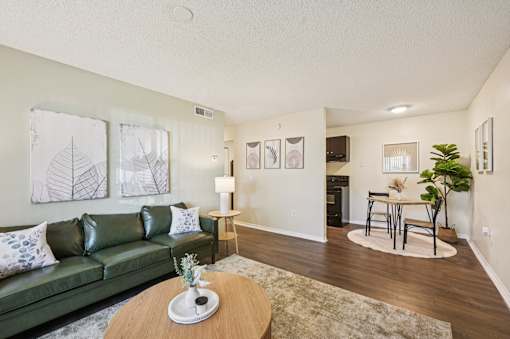 A living room with a green couch, a coffee table, and a dining area in the background. at Sarasota South Apartments, Bradenton