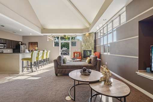 A living room with a brown carpet and a round table with a vase on it.