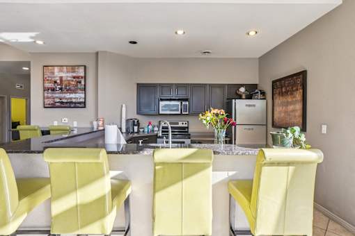A kitchen with yellow chairs and a fridge.