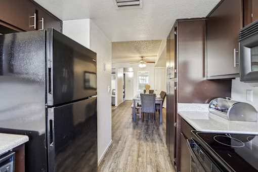 A kitchen with a black refrigerator and brown cabinets at Del Coronado Apartment , Arizona, 85202
