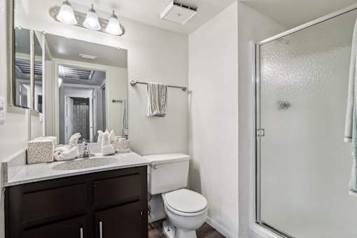 A white toilet sits next to a sink in a bathroom at Del Coronado Apartment, Mesa, AZ, 85202