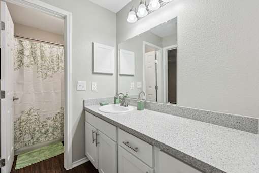 A bathroom with a sink, mirror, and shower curtain.