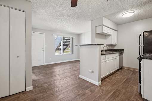 A kitchen with white cabinets and a wooden floor. at Windmill Apartments, Colorado Springs, Colorado