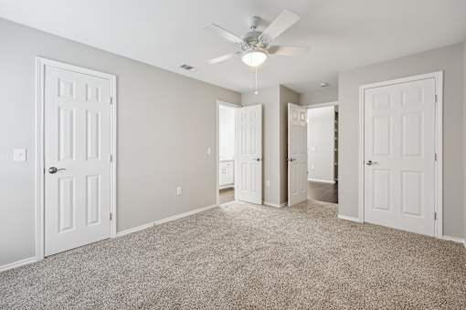 A spacious room with a carpeted floor and a ceiling fan.