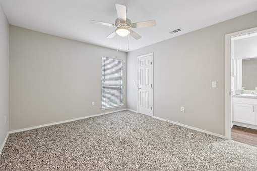 A room with a ceiling fan and carpeted floor.
