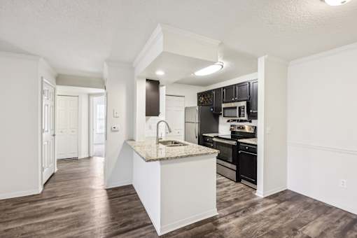 A kitchen with a white island and dark wood floors at The Parkway at Hunters Creek, Orlando, 32837