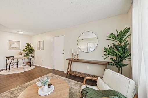 A living room with a couch, a coffee table, and a mirror on the wall. at Sarasota South Apartments, Bradenton, Florida