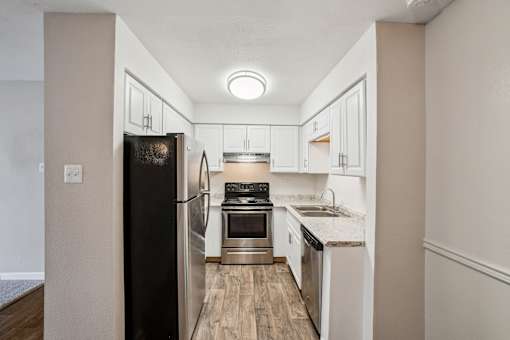 A kitchen with a black refrigerator and white cabinets. at Glen at Lakewood, Colorado
