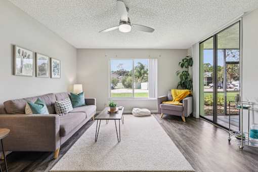 A living room with a grey couch, a coffee table, and a yellow throw pillow. at Lakeside Glen Apartments, Melbourne