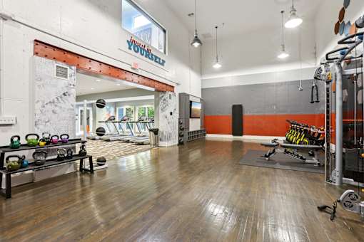 A gym with a variety of equipment including a squat rack, kettlebells, and a bench press. at Canopy Glen, Norcross, GA