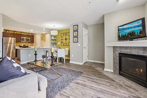 A modern living room with a grey couch and a fireplace.