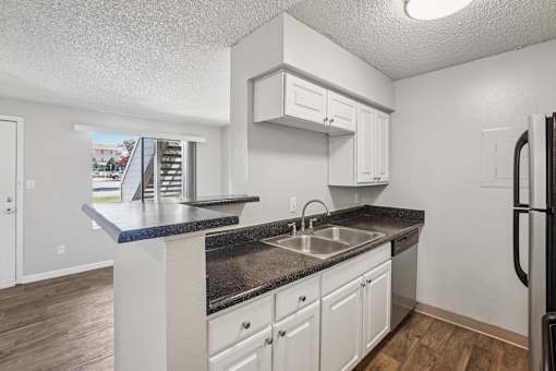 A kitchen with white cabinets and a black countertop. at Windmill Apartments, Colorado