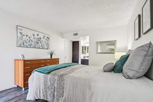 A bedroom with a bed, nightstand, and a plant at Del Coronado Apartment , Mesa, Arizona