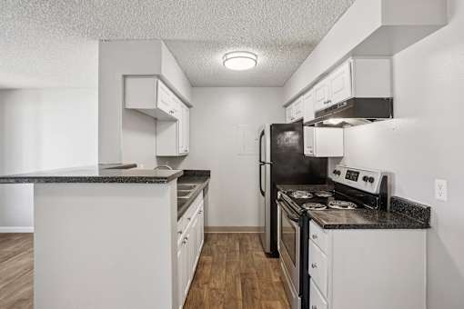 A kitchen with white cabinets and a black countertop. at Windmill Apartments, Colorado Springs